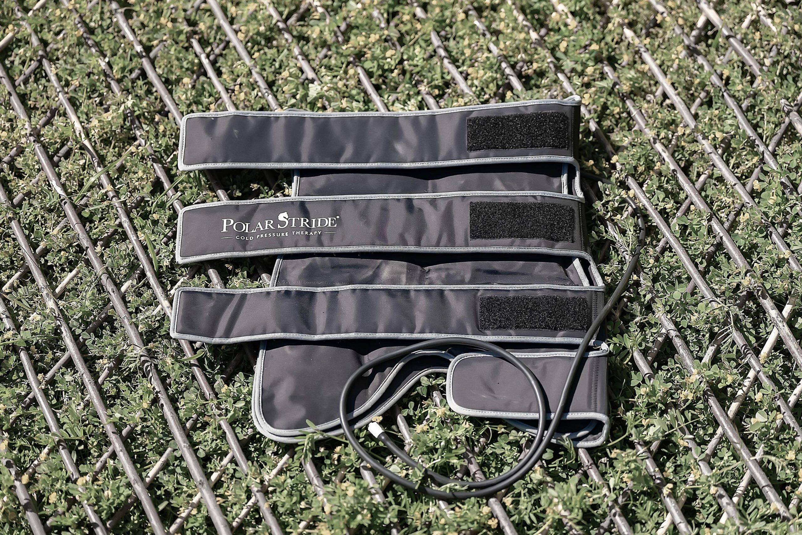 Polar Stride cold-compression wrap laid out flat, showing the three adjustable velcro straps and connecting tube