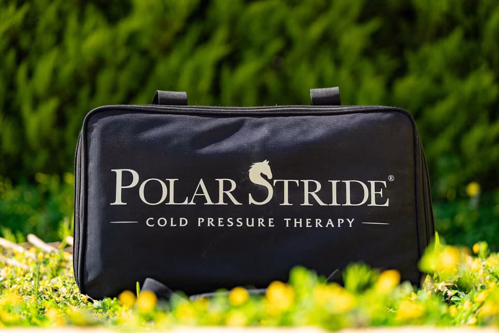 Polar Stride portable cold-compression recovery kit in its branded carrying case, photographed outdoors in a sunlit meadow