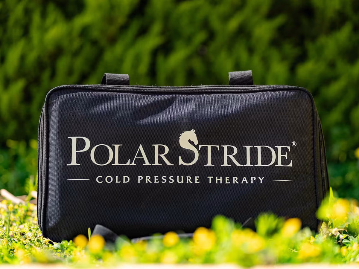 Polar Stride portable cold-compression recovery kit in its branded carrying case, photographed outdoors in a sunlit meadow